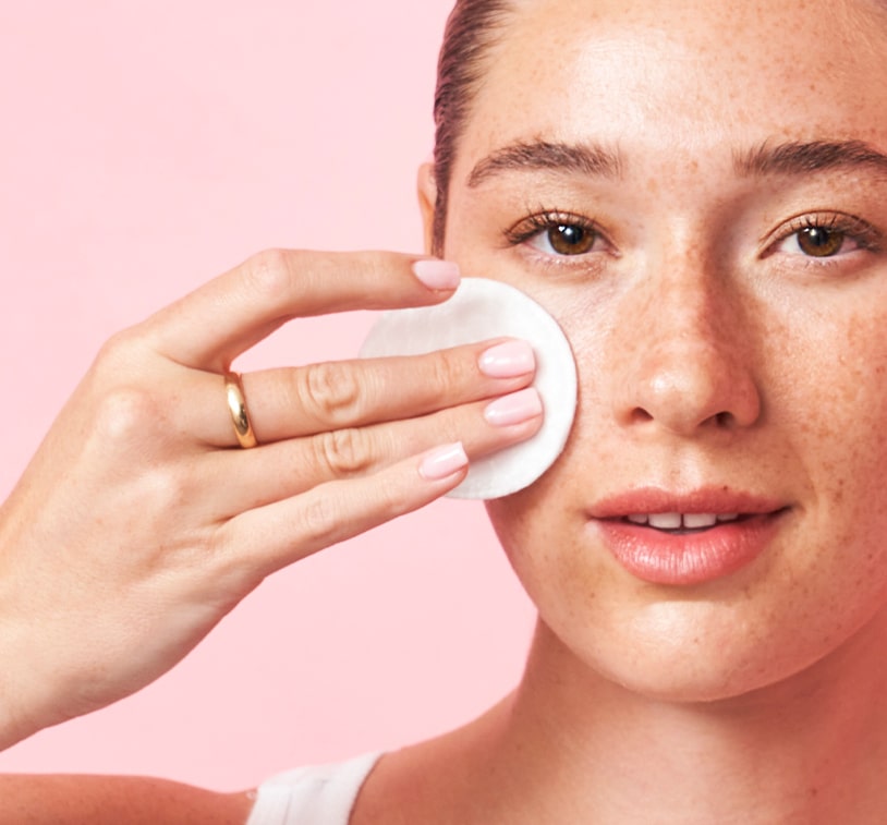 Person applying MONAT Micellar Water on a cotton pad.