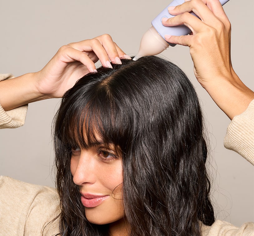 Model applying MONAT Scalp Comfort Treatment directly to her scalp with the tube nozzle.