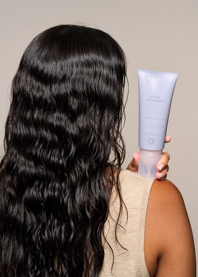 Model facing backward holding a MONAT Scalp comfort treatment tube over her shoulder