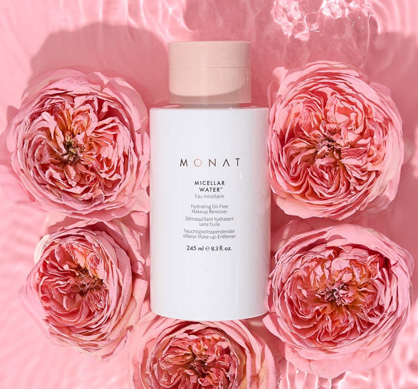 Bottle of MONAT Micellar Water surrounded by pink roses.