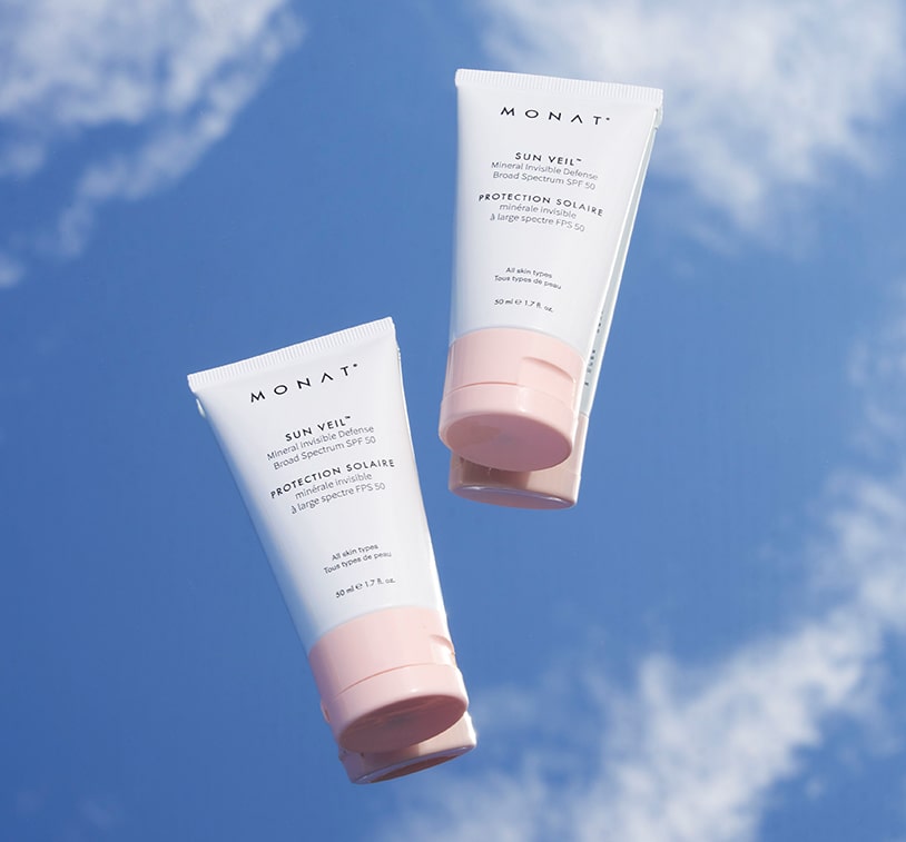 two tube Sun Veil Mineral Invisible Defense-Broad Spectrum-SPF-50 floating against a bright blue sky with light clouds.