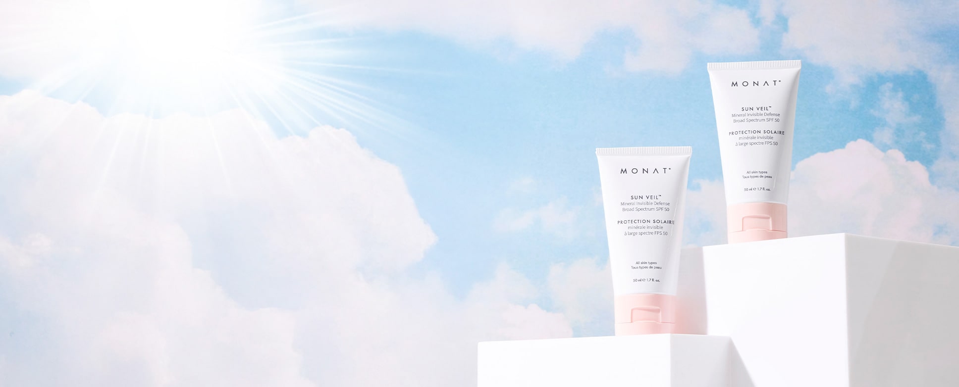 Two tubes of Sun Veil SPF 50 sunscreen on a white pedestal against a backdrop of sunny sky.