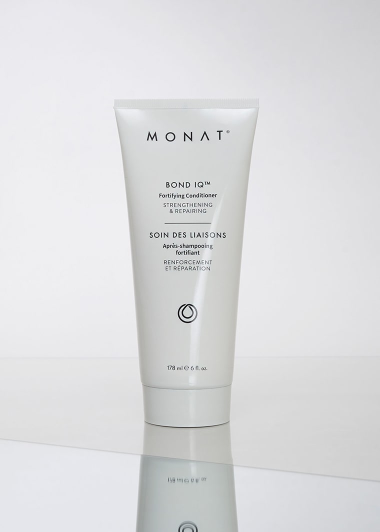 Product shot of a white MONAT BOND IQ Fortifying Conditioner tube standing upright on a reflective white surface against a light gray background
