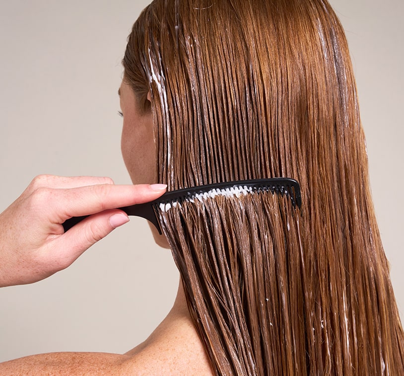 Close-up side view of a woman using a comb to detangle wet hair
