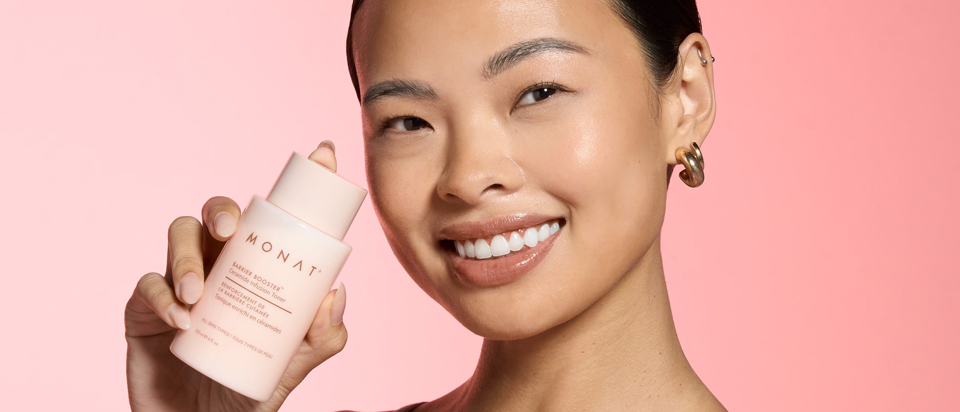 Close-up of a woman with glowing skin, smiling while holding the toner bottle next to her cheek