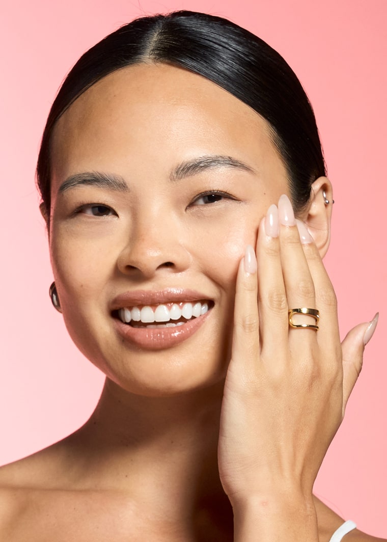 Woman laughing while applying MONAT Barrier Booster™ Ceramide Infusion Toner to her face