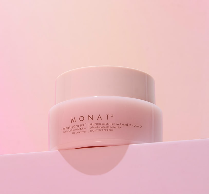 Close-up of MONAT Barrier Booster™ Barrier Defense Moisturizer jar on a light pink surface.