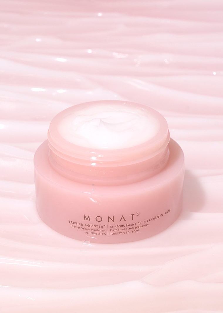 Open jar of MONAT Barrier Booster™ Barrier Defense Moisturizer showing creamy texture, placed on a pastel pink background.