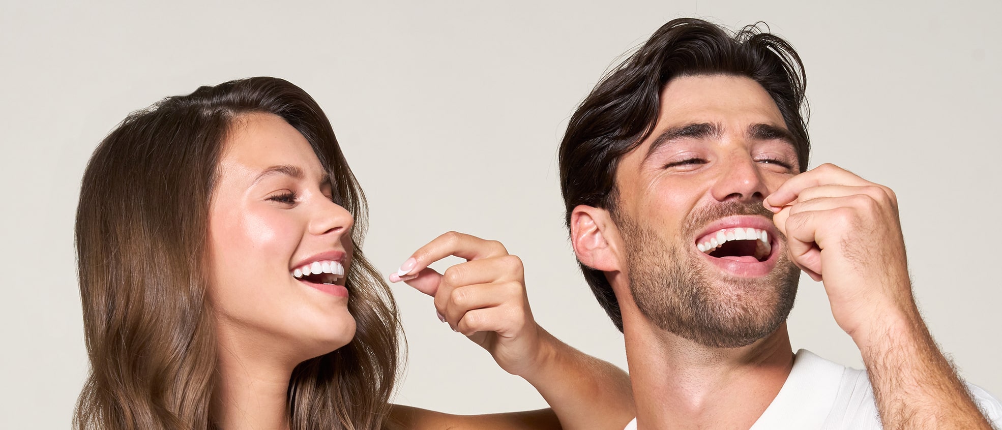 Man and woman laughing while holding supplement capsules