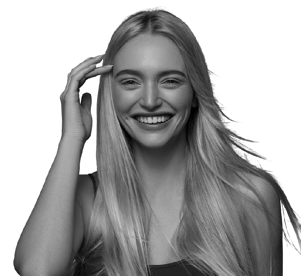 Smiling blonde woman with long hair touching her face with one hand, overlaid with text 'Introducing the Stylist Program