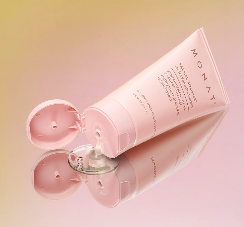 MONAT Barrier Booster cleanser tube next to round pink compact mirror on beige textured surface