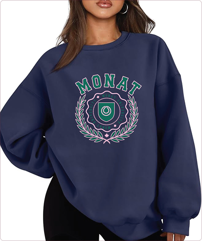A woman wearing a navy blue oversized sweatshirt with a decorative MONAT U emblem printed on the front.