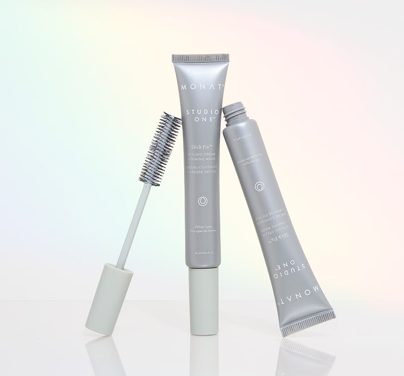 Front-facing MONAT Studio One Slick Fix™ Styling Cream Taming Wand on a prism light background, featuring one closed tube and one open wand with brush applicator.