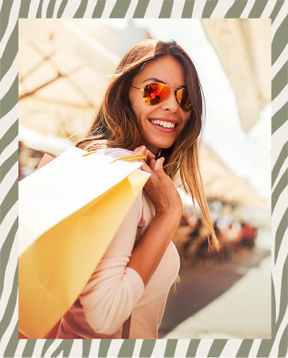 woman wearing orange-tinted sunglasses carrying yellow and white shopping bags over her shoulder