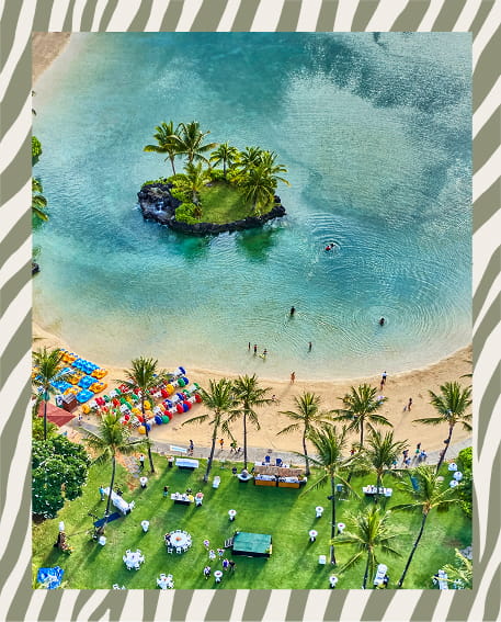 Aerial view of turquoise ocean waters meeting a curved sandy beach with lush green tropical vegetation along the coastline