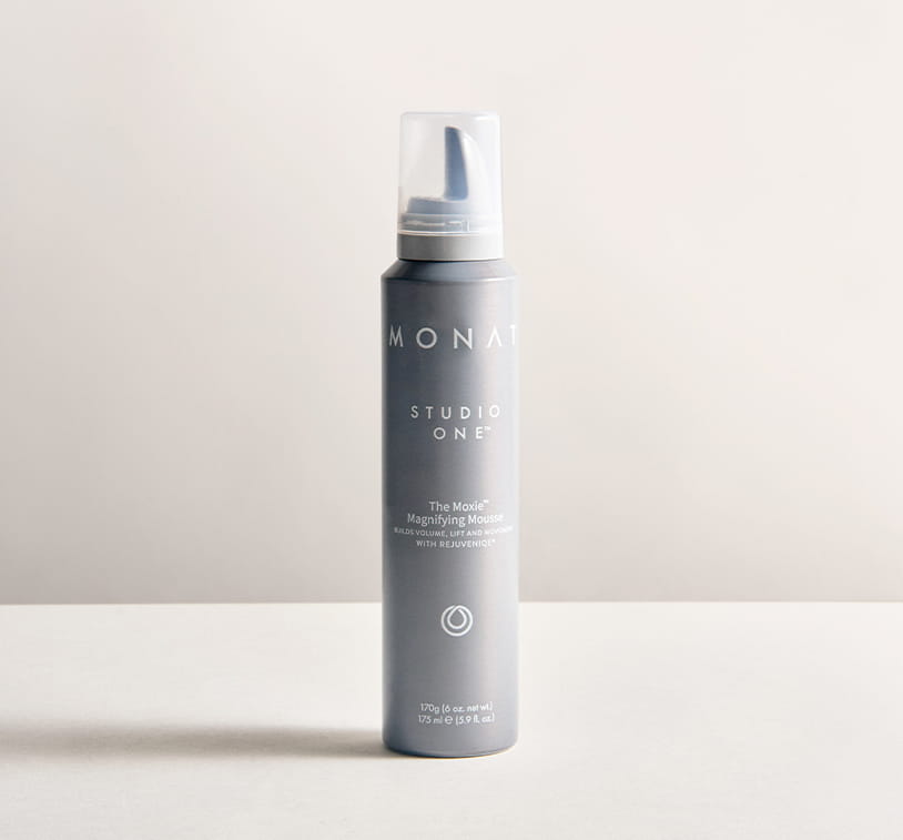 Monat Studio One™ The Moxie™ magnifying mousse bottle on a neutral background.