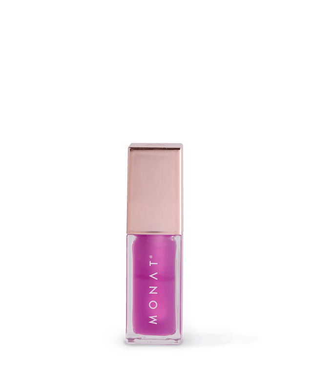 Purple MONAT lipstick in a clear square tube with a rose-gold cap, on a pale shadow against a black background.