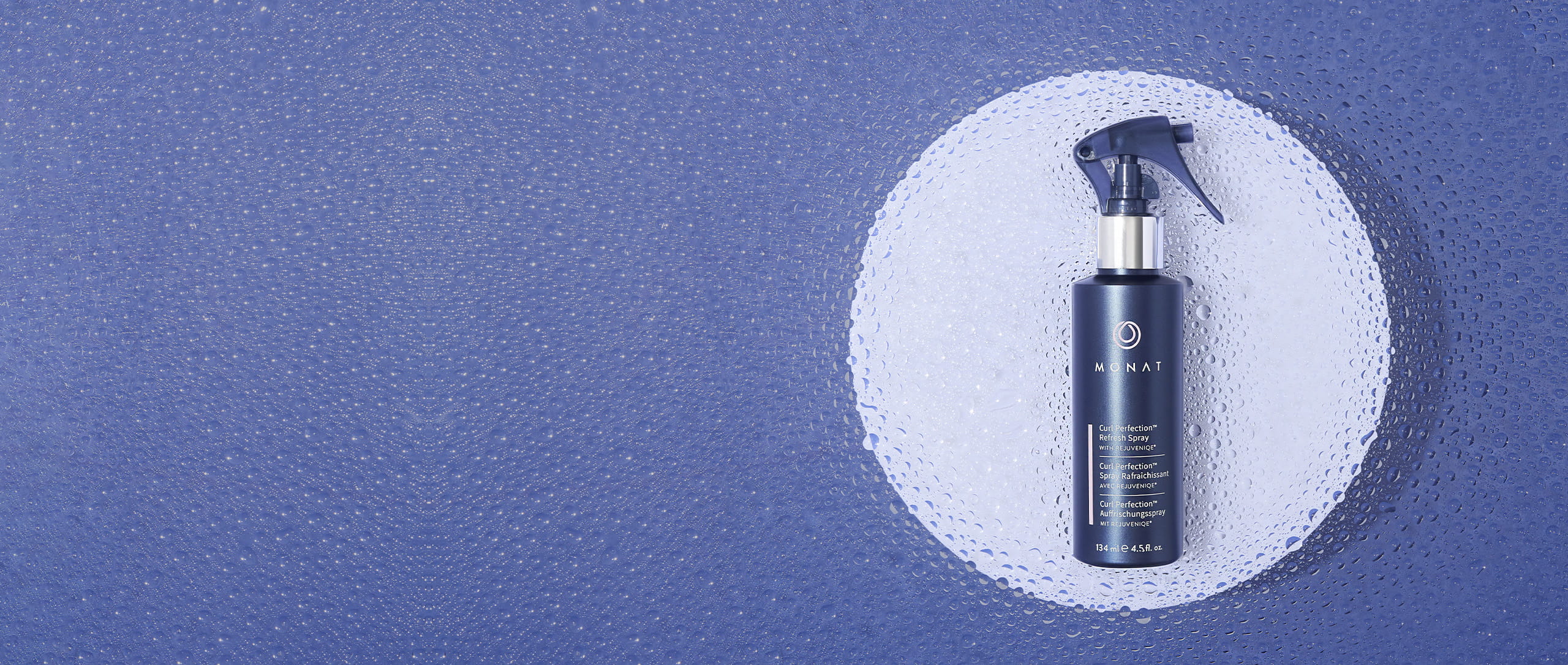 MONAT Curl Perfection spray bottle on a white circular platform, positioned on the right side of a blue background covered in water droplets.