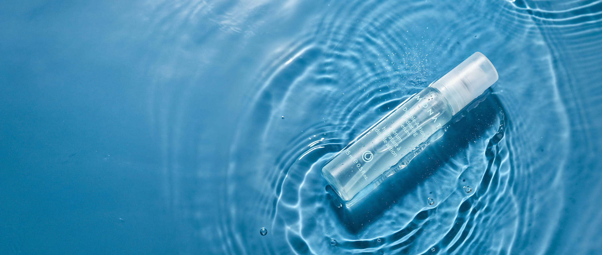  Double Action Hydrating Serum bottle floating on blue water with soft ripples and light reflections.