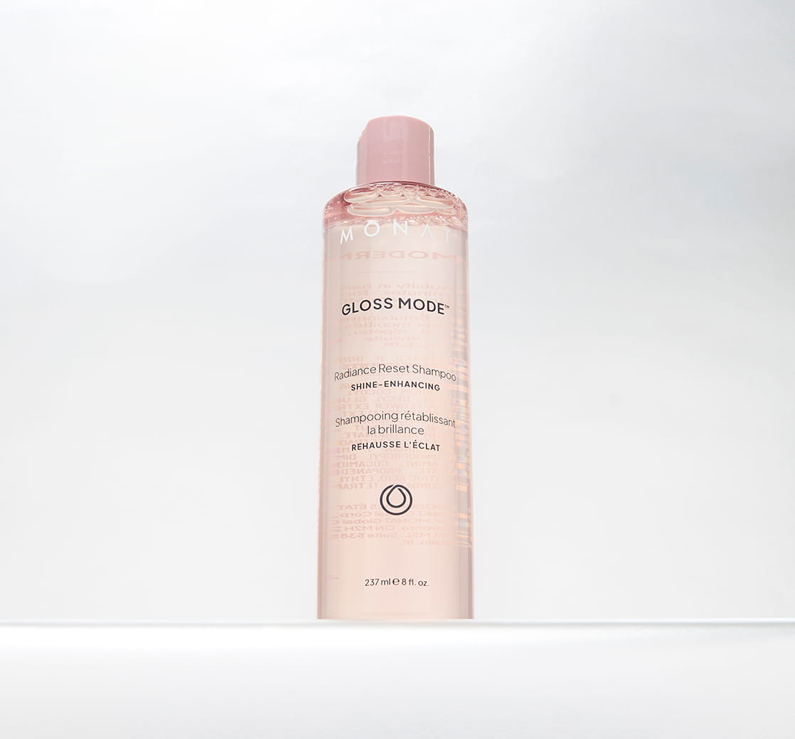 Close-up of a clear pink Gloss Mode Radiance Reset Shampoo bottle with a pink cap against a clean white background