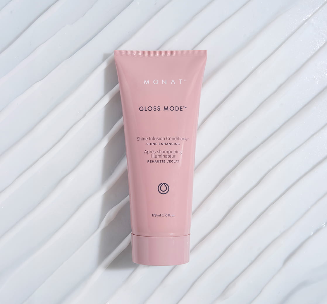 Pink MONAT Gloss Mode Shine Infusion Conditioner tube displayed on a white ridged background.