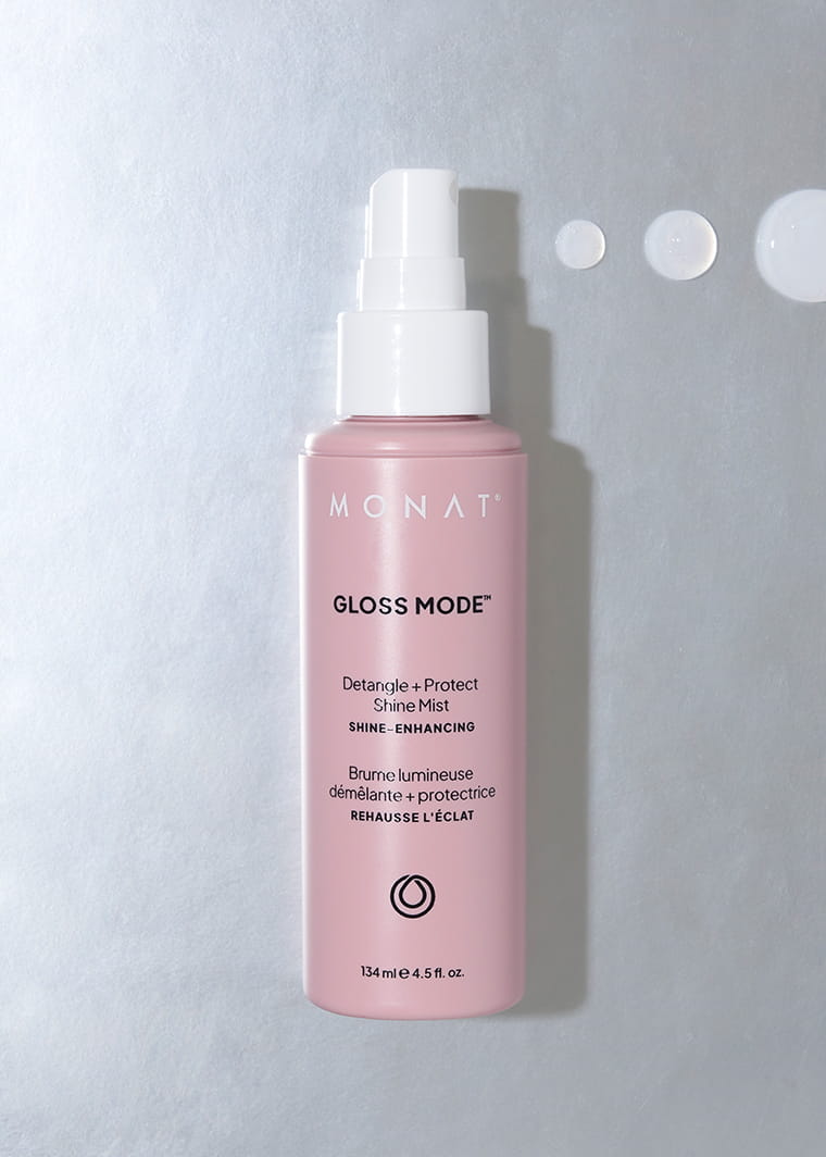 MONAT Gloss Mode Shine Mist bottle standing on a light surface with droplets of product nearby